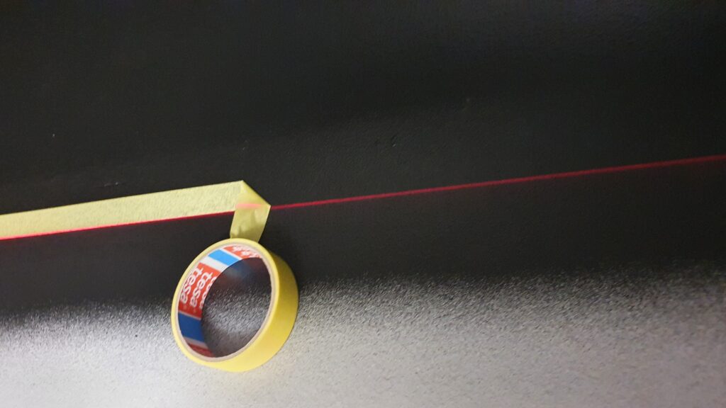 Masking tape on laser level line. Gocolorize.com